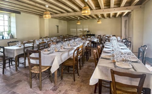 Élégante salle à manger de Cour Du Liège avec tables drapées de blanc, chaises en bois et luminaires suspendus à Baugé-en-Anjou