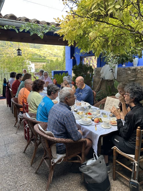Clients dînant en plein air à Casa Gallinera à Alicante, Espagne, sous une pergola avec vue sur les montagnes.