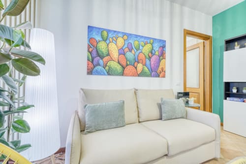 Elegante soggiorno al lussuoso B&B SleepWithMe di Pisa con divano crema, arte con cactus colorati, parete verde e piante in vaso