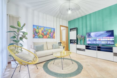 Soggiorno moderno con parete accent turchese, divano crema, poltrona gialla e TV a schermo piatto presso SleepWithMe Luxury B&B a Pisa