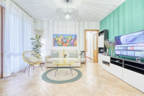 Elegante soggiorno con parete verde menta, divano color crema, poltrona gialla e TV a schermo piatto in lussuoso appartamento B&B a Pisa