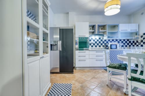 Cucina moderna con rivestimento a quadretti blu e bianchi, mobili bianchi e forno verde in esclusiva camera B&B a Pisa