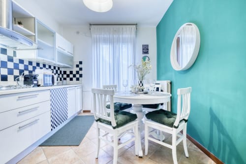 Cucina e zona pranzo moderna della lussuosa B&B di Pisa con parete azzurra, mobili bianchi e rivestimento a scacchiera