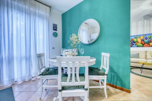 Raffinata sala da pranzo in lussuoso B&B pisano con parete azzurra, tavolo rotondo bianco e specchio circolare