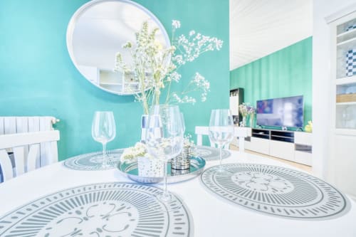 Elegante sala da pranzo con pareti turchesi, tavolo bianco, calici di vino e fiori freschi presso il lussuoso B&B SleepWithMe
