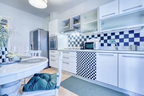 Cucina moderna blu e bianca con backsplash a quadretti, elettrodomestici in acciaio inox e zona pranzo in lussuoso appartamento a Pisa