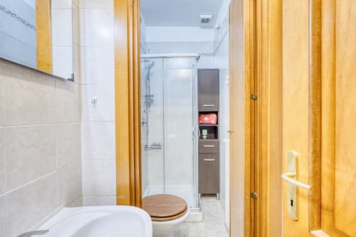Bagno moderno con dettagli in legno, piastrelle bianche, servizi igienici, doccia walk-in e mobiletti a Evergreen Luxury B&B a Pisa