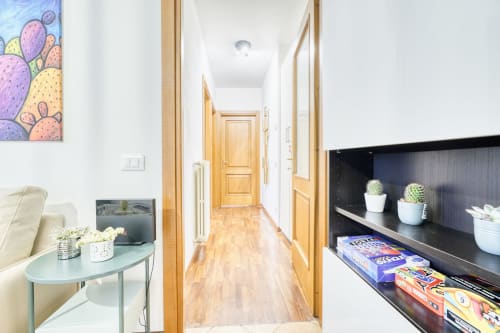 Corridoio moderno in appartamento di lusso a Pisa con porte in legno, piante grasse in vasi su scaffali neri e opere d'arte con cactus colorati
