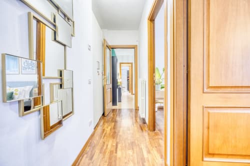 Corridoio moderno nella lussuosa suite B&B di Pisa con porte in legno, pareti bianche e pavimento in legno duro