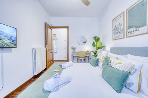 Luminosa camera di lusso al SleepWithMe B&B di Pisa con vista giardino, letto con cuscini verdi, TV, scrivania e arredamento moderno