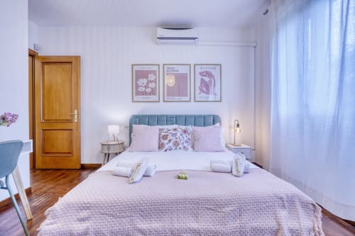 Camera moderna al SleepWithMe Luxury B&B di Pisa con testata teal, accenti rosa, porta in legno e aria condizionata