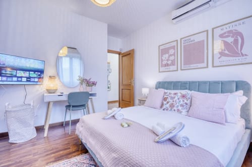 Lussuosa camera nel B&B di Pisa con letto matrimoniale, scrivania trucco, TV e comfort moderni, vista giardino e arredamento elegante.