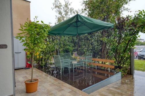 Area relax con ombrellone verde, piante in vaso e edera rampicante presso SleepWithMe luxury B&B a Pisa