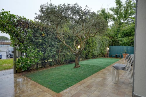 Giardino privato esclusivo di SleepWithMe Luxury B&B a Pisa con prato curato, alberi maestosi e zona lounge