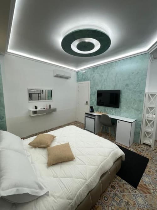 Habitación Familiar Deluxe del Hotel Boutique Galeón Calpe con iluminación moderna, cama blanca y acentos turquesas