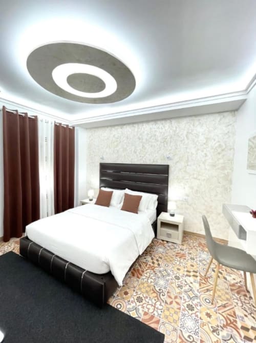 Moderno dormitorio de hotel en Hotel Boutique Galeon en Calpe con cama negra, luces de techo circulares, cortinas burdeos y