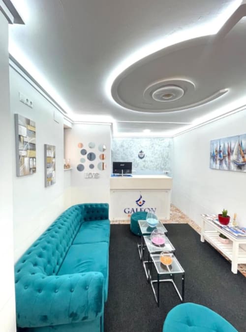 Habitación moderna del hotel boutique Galeon en Calpe con asientos turquesas, mostrador de recepción y diseño contemporáneo del techo