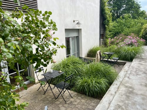 Patio privé du studio Denis & Virginie à Versailles avec chaises noires, herbes ornementales, fleurs en bloom et design moderne
