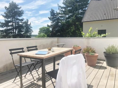 Terrasse ensoleillée de la chambre d'hôtes Denis & Virginie à Versailles avec table à manger, plantes en pot et vue sur les arbres