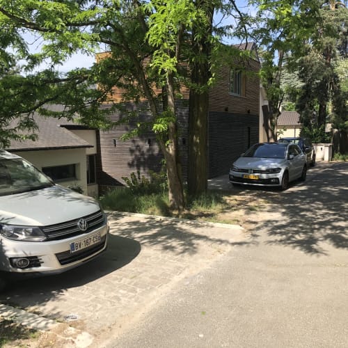 Allée du gîte Denis & Virginie à Versailles avec voitures garées et immeuble moderne entouré d'arbres