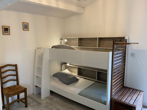 Lits superposés dans la chambre du Petit Moulin B&B à Pouzauges, France, avec chaise en bois et rangements