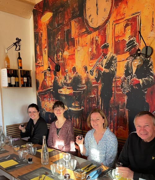 Quatre clients dînant au gîte Le Petit Moulin à Pouzauges, devant un décor d'œuvres d'art orange vibrant