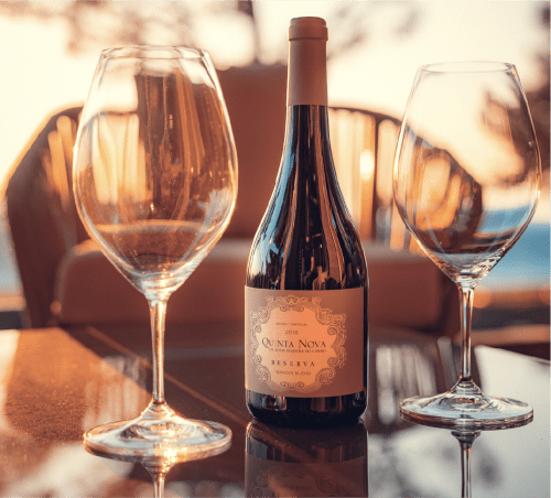 Taças de vinho e garrafa na Charm Nature B&B em Azóia, Portugal durante o pôr do sol da hora dourada