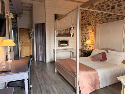 Chambre double romantique aux Instants Volés avec lit à baldaquin, cheminée, murs en pierre et équipements modernes à Tudeils