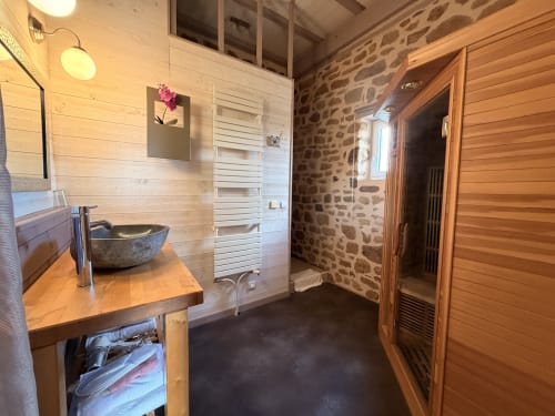 Salle de bain spa aux Instants Volés avec sauna en bois, murs en pierre, vasque et sèche-serviettes