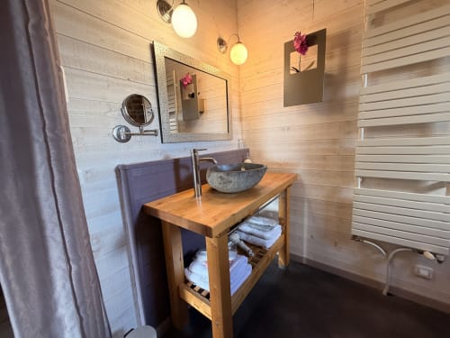 Salle de bain spa moderne aux Instants Volés avec vanité en bois, vasque, sèche-serviettes chauffant et équipements spa