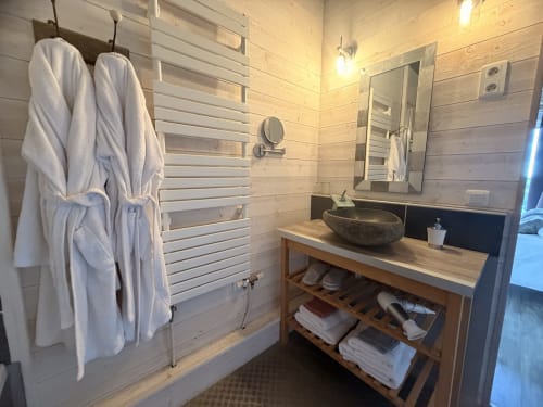 Salle de bain moderne aux Instants Volés avec vanité en bois, lavabo en pierre, sèche-serviettes chauffant et peignoirs blancs à Tudeils