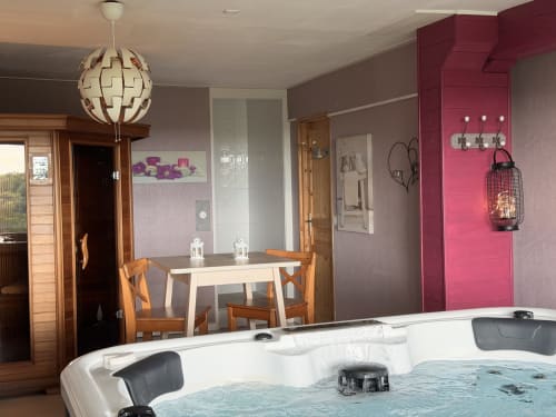 Suite spa luxe aux Instants Volés avec jacuzzi, table à manger en bois et mur accent lie-de-vin à Tudeils