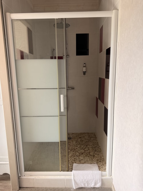 Douche moderne aux parois de verre dépoli et sol en galets à l'hôtel-boutique Les Instants Volés à Tudeils,