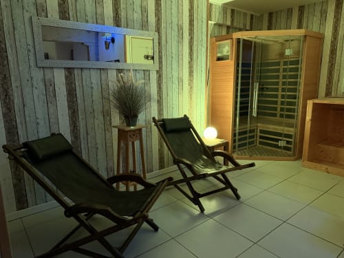 Espace détente spa aux Instants Volés avec sauna, chaises longues, miroir et lumière douce à Tudeils