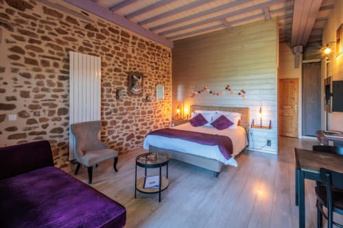 Chambre double luxueuse aux murs en pierre, accents violets et équipements modernes aux Instants Volés à Tudeils