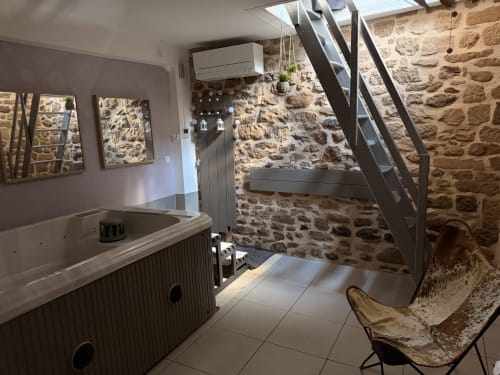 Salle de bain spa luxe aux murs de pierre, jacuzzi privé, vasque moderne et escalier métallique aux Instants Volés, Tudeils
