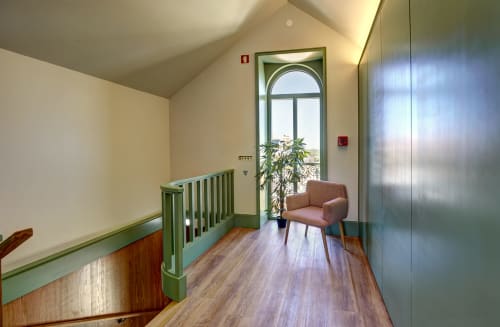Sintra Green Chalet landing area with wooden floors, green railings, arched window, potted plant, and lounge chair