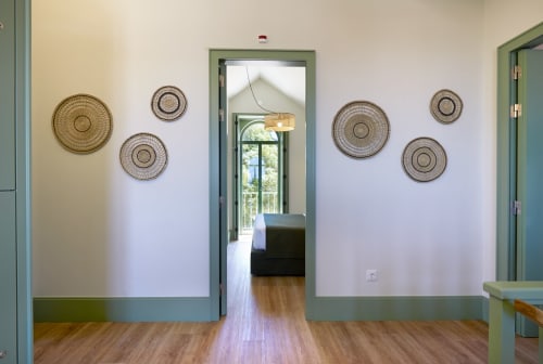 Corredor moderno com acabamento verde sálvia e arte em parede com cesto tecido na Sintra Green Chalet, pisos de madeira