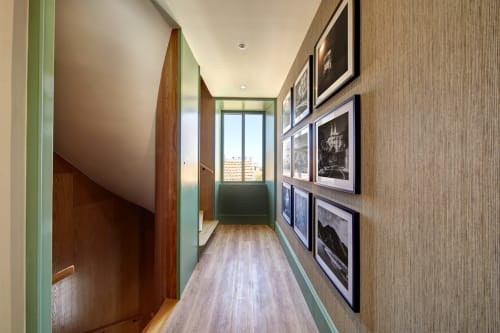 Hallway at Sintra Green Chalet with framed black and white photographs, green trim, wooden doors, and natural light from