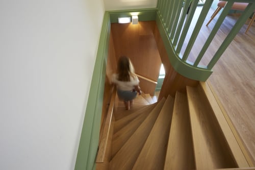 Wooden staircase at Sintra Green Chalet B&B with guest descending to ground floor, green railings visible
