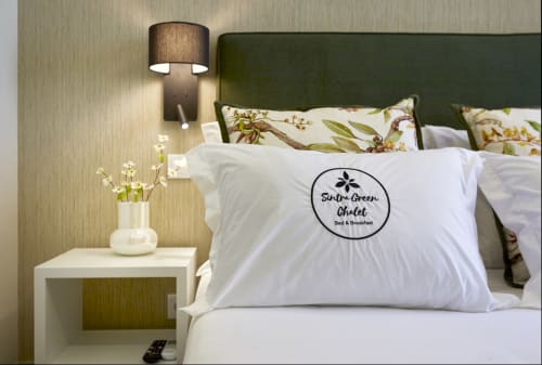 Sintra Green Chalet bedroom with green headboard, white pillows, floral bedding, nightstand with lamp and flowers