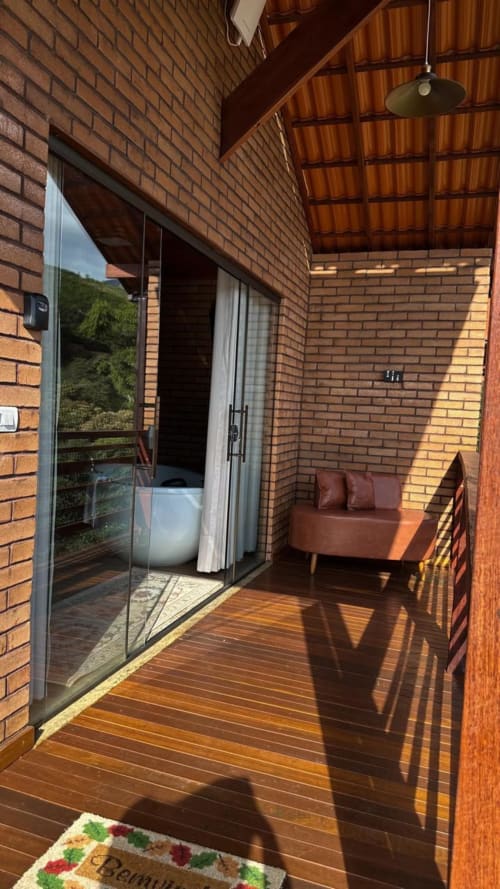 Varanda privada em Vivendas Canaã com deck de madeira, paredes de tijolos, vista para as montanhas e móveis modernos em Espera Feliz