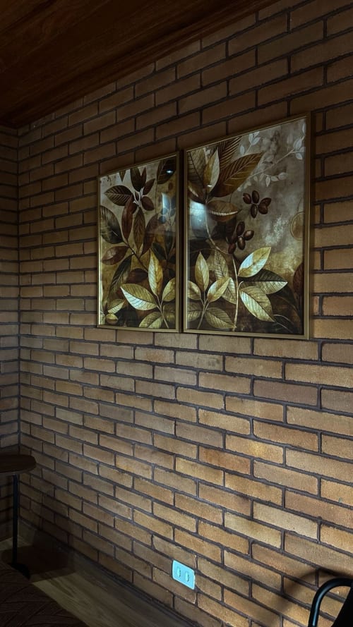 Dois quadros de arte botânica com folhas e flores na parede de tijolos da villa Vivendas Canaã
