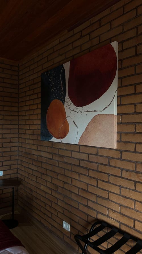 Obra de arte moderna abstrata com formas em bordô, ferrugem e creme na parede de tijolos da villa Vivendas Canaã em Espera Feliz
