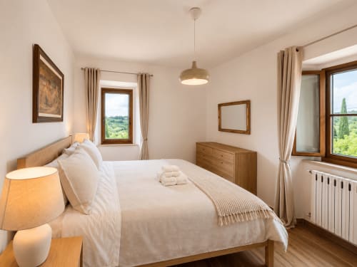 Serena bedroom at Tuscan Sun Stays with wooden bed, mountain views, pendant light, and Tuscan countryside visible through