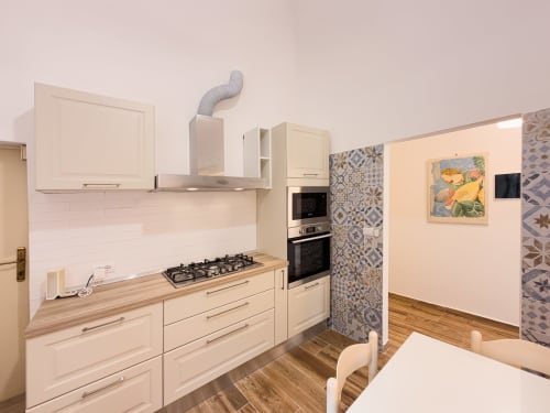 Modern kitchen in Serena apartment at Tuscan Sun Stays with cream cabinets, gas stove, and patterned backsplash tiles.