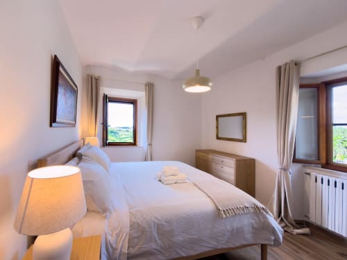Bright Serena bedroom at Tuscan Sun Stays with mountain views, white linens, wooden furniture, and pendant lighting in