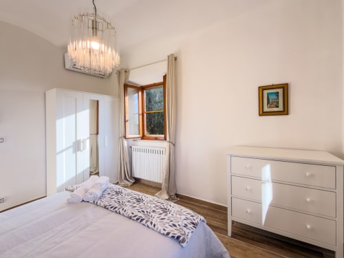Bright bedroom at Tuscan Sun Stays with white wardrobe, dresser, window with mountain views, pendant light, and striped
