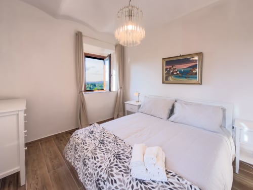 Bright bedroom in Serena apartment at Tuscan Sun Stays with mountain views, white bed, elegant chandelier, and modern