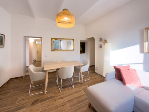 Modern dining area with wooden table, white chairs, and woven pendant light in Serena apartment at Tuscan Sun Stays, Lajatico